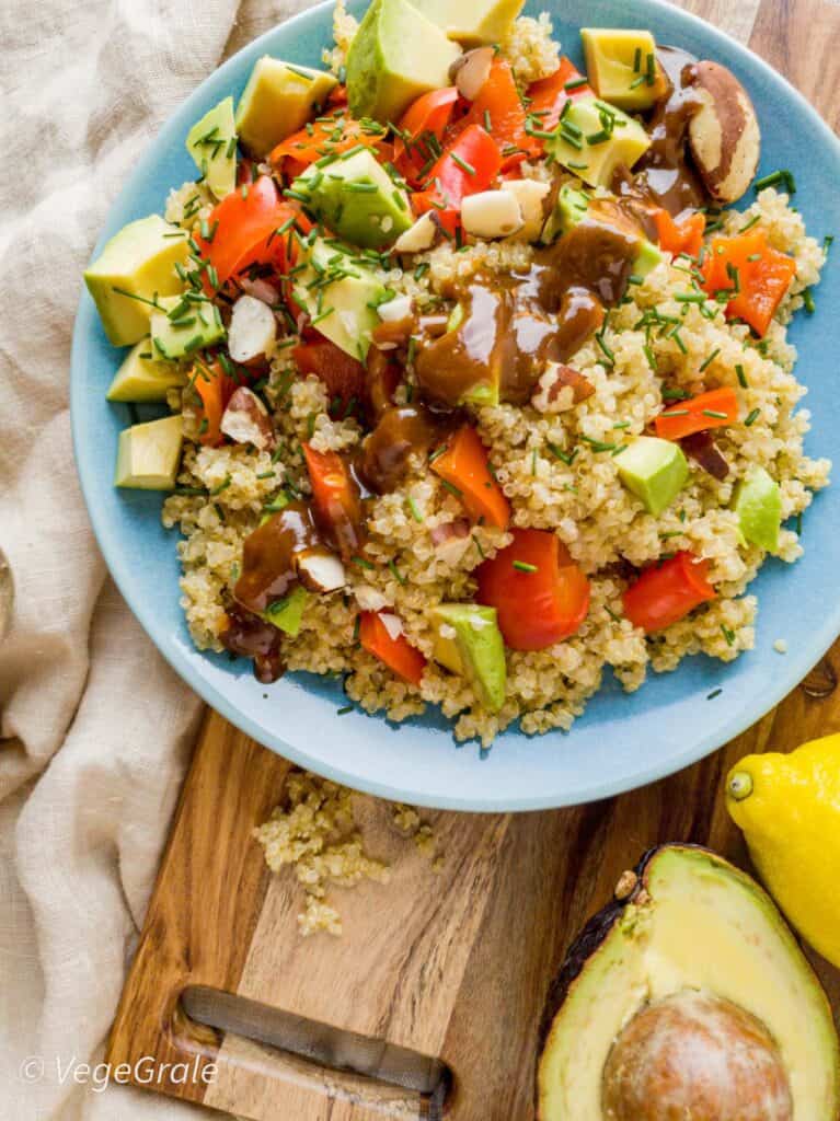 piatto di quinoa cotta condita con peperoni, avocado, noci brasiliane e salsa