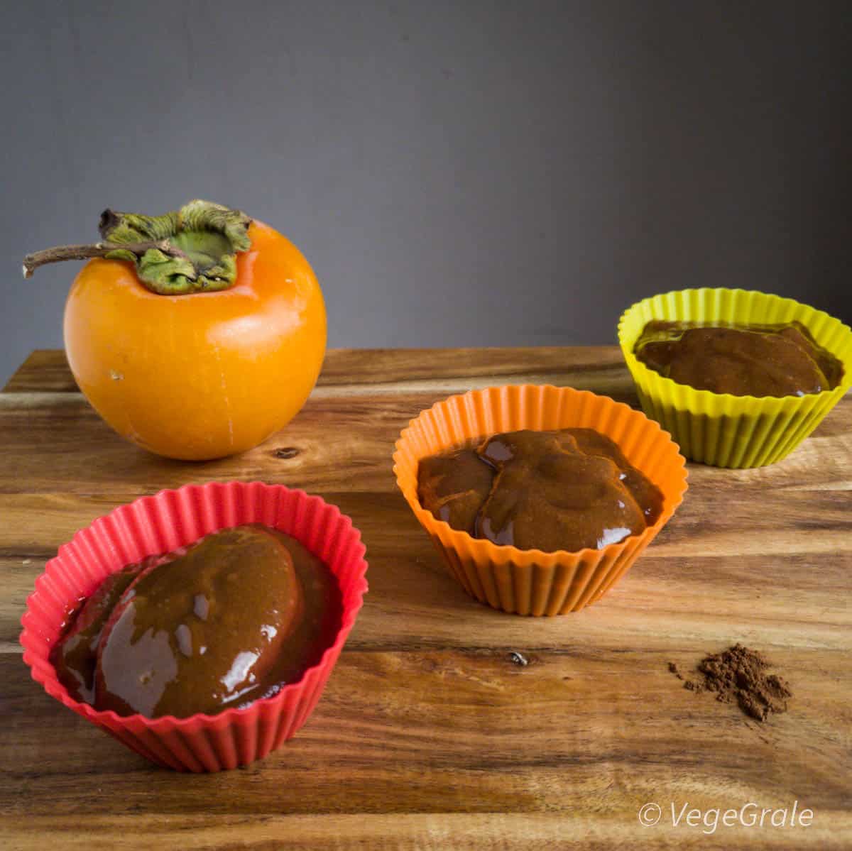 budino cachi e cacao in pirottini di silicone colorati, caco in sottofondo