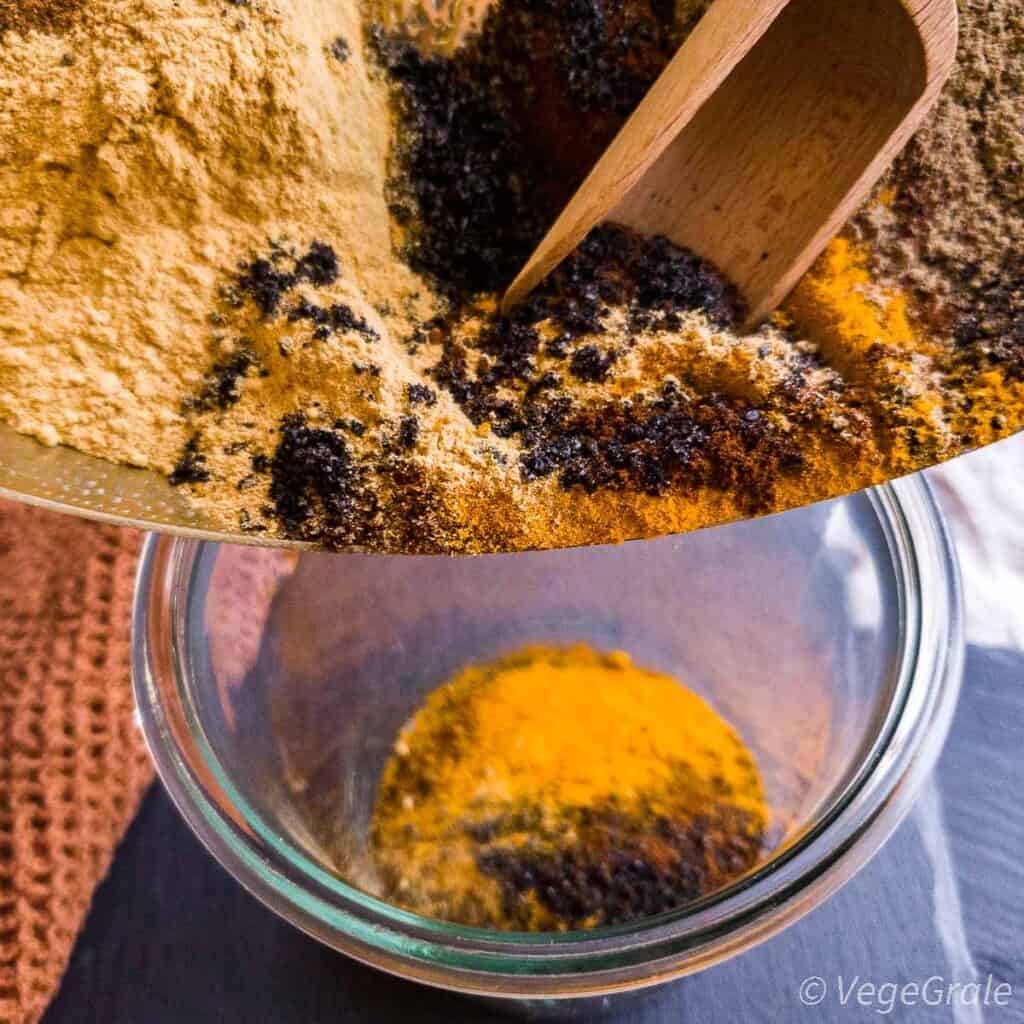 Le spezie diverse in polvere vengono travasati in un vaso di vetro, per poterli mischiare meglio.