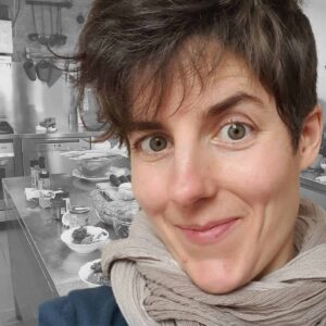 Ritratto di Angelika de Beauclair di fronte alla foto dell'interno di una cucina (ma i colori della cucina sono bianco e nero, mentre la faccia è in colore).