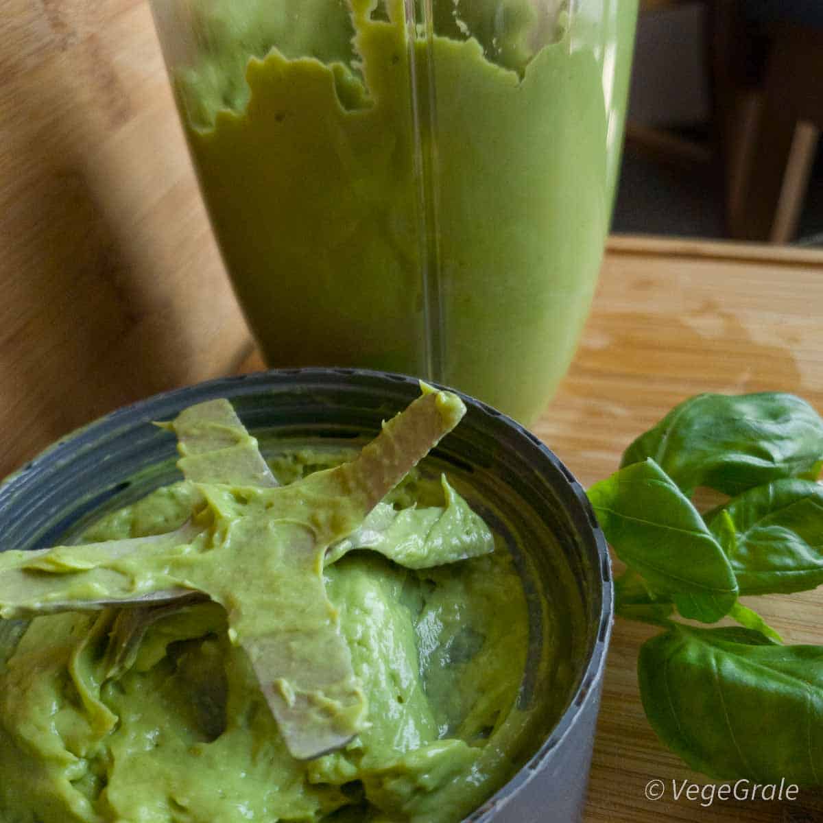 Crema di avocado appena frullata nel boccale del frullatore aperto, le lame del frullatore sono ancora sporche della crema omogenea.