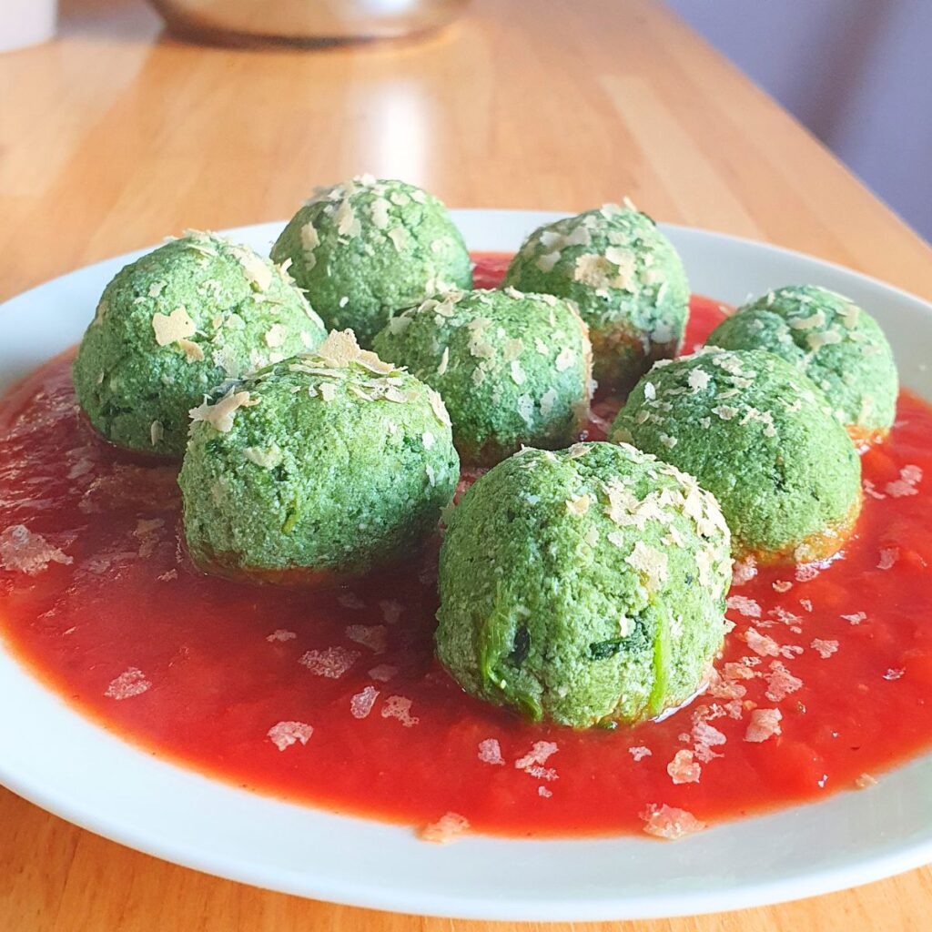 Gnudi verdi di spinaci e ricotta vegana su salsa di pomodoro