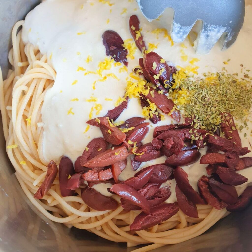 Spaghetti in pentola con ricotta vegana, olive kalamata, scorza di limone e origano prima di mescolare
