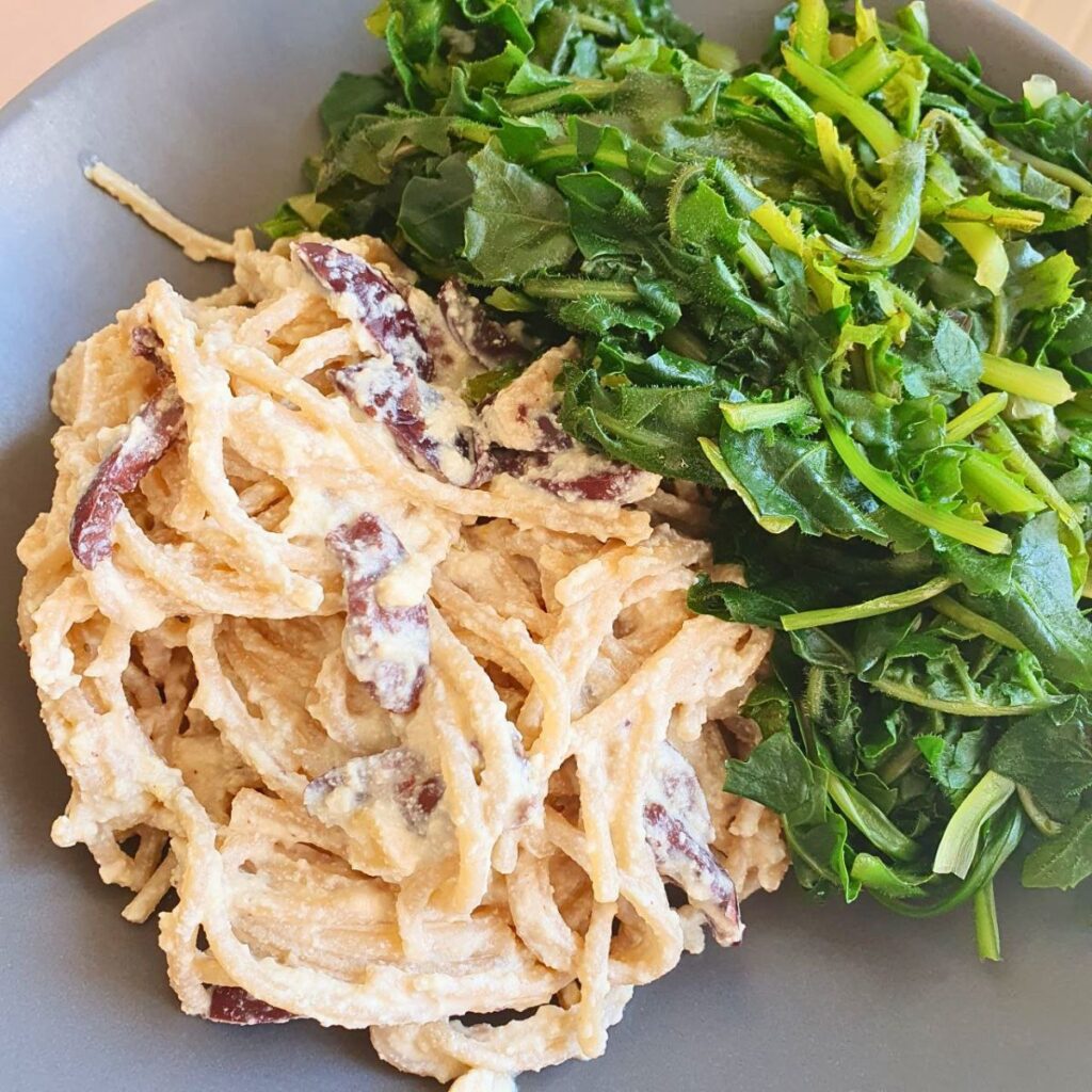 Spaghetti integrali con ricotta vegana di tofu e olive kalamata, serviti con erbe di campo